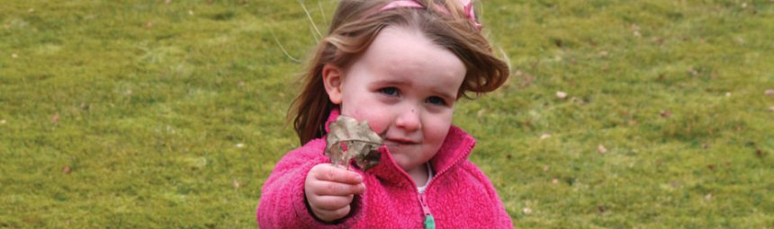 A toddler holding a leaf
