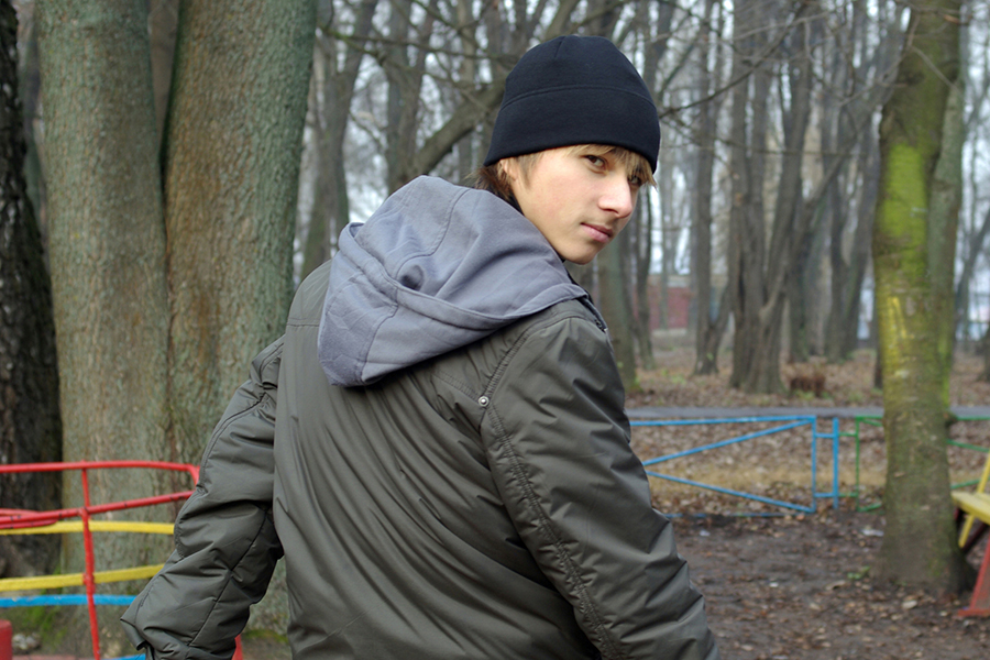 young man looking over shoulder towards camera in wooded area