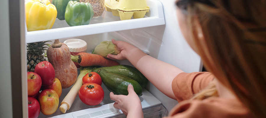 A young person taking food out of a fridge