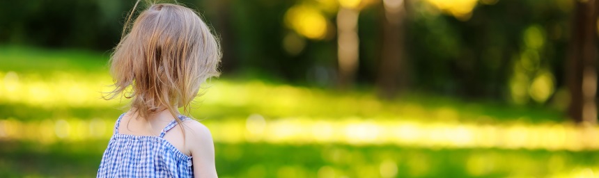 A girl, photographed from behind, in a garden