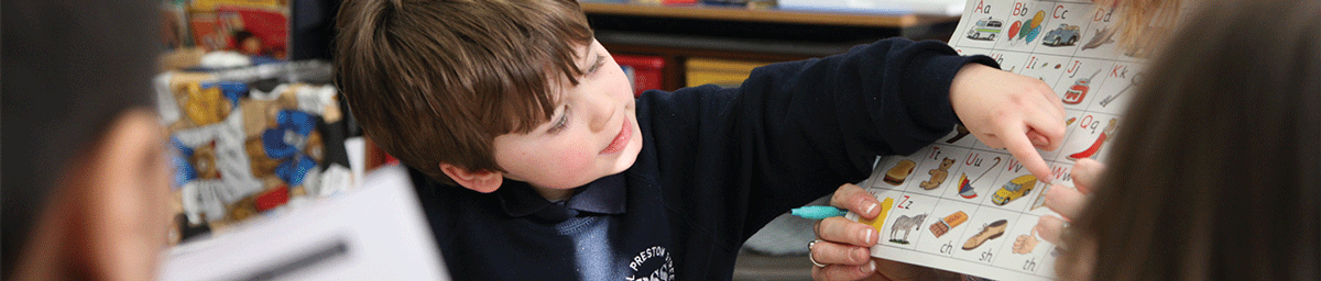 A boy at school pointing to his work