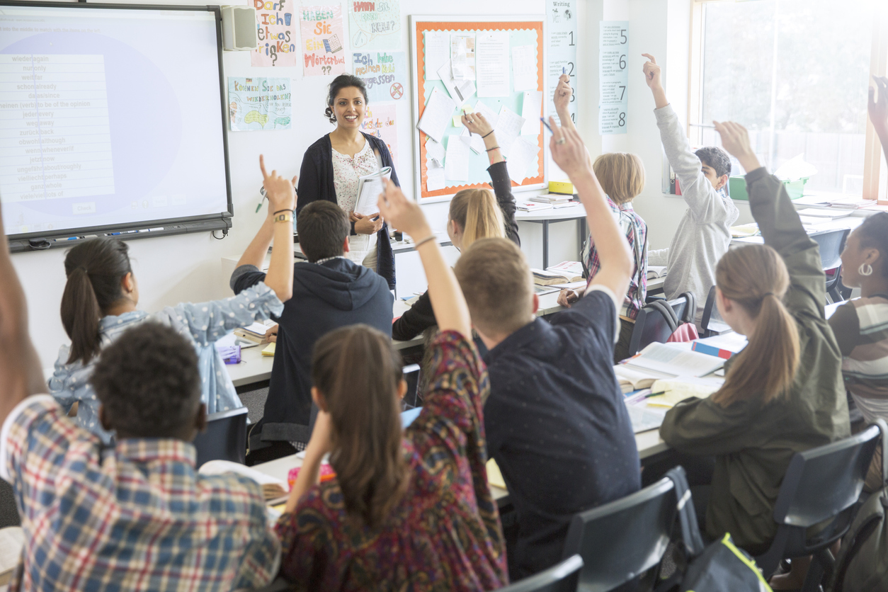 Pupils all trying to answer a question in class by raising their hand