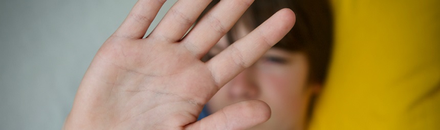 A young person holding up a hand in front of their face