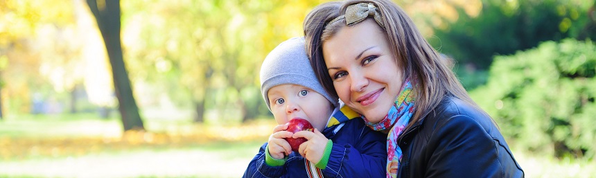 A mother holding her baby in a park