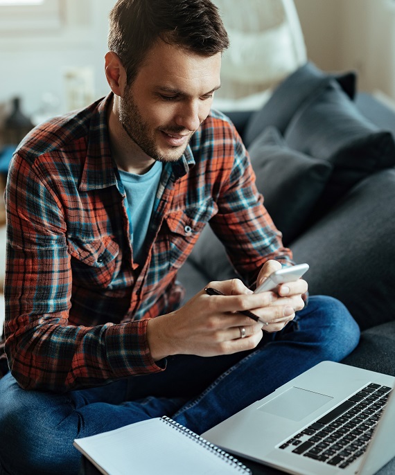 A man on his mobile phone, in front of a computer.