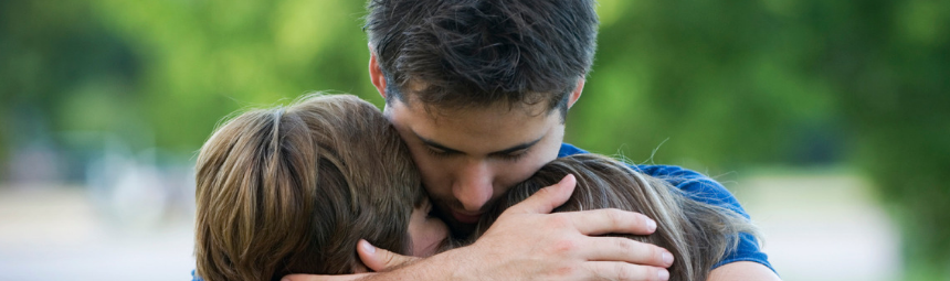 A parent hugging their son and daughter