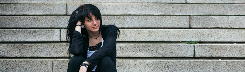 A teenager sitting on some steps outside