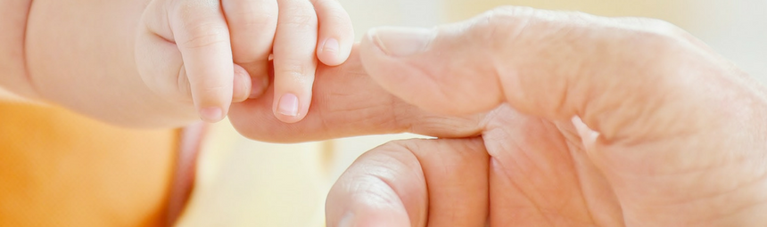 A baby's hand holding an adult's finger