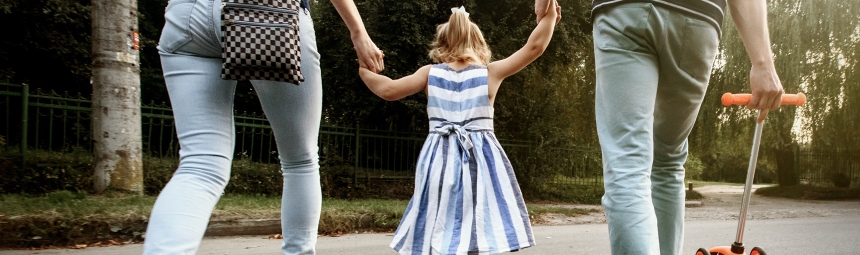 A child holding hands with two adults