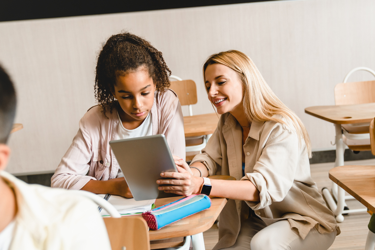 A teacher helping a pupil at her desk