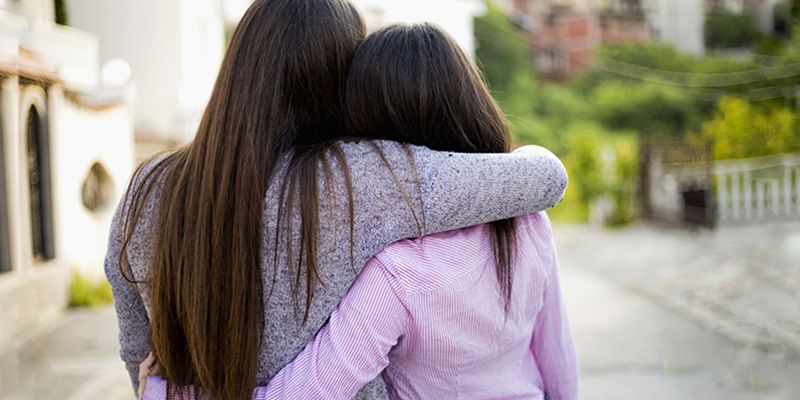 An adult and teenager hugging