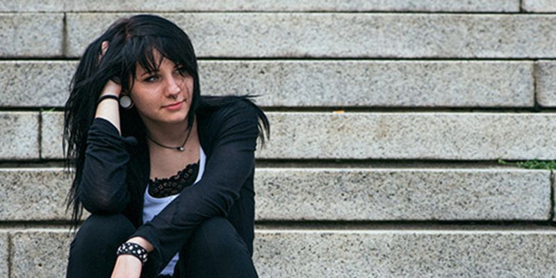 A teenager sitting on some steps