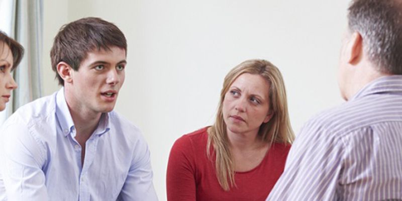 people listening to a young man in a meeting