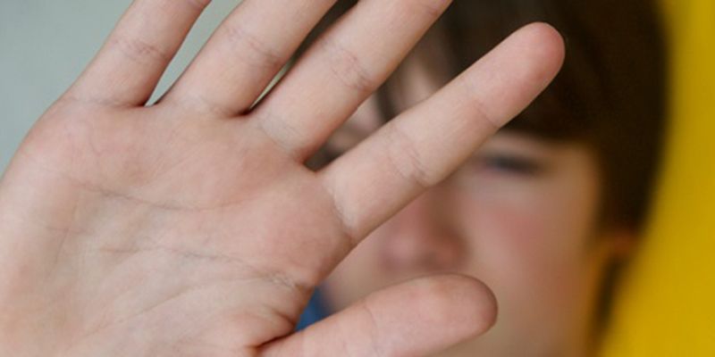 A child defensively holding his hand in front of his face