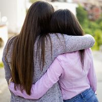 An adult and teenager hugging