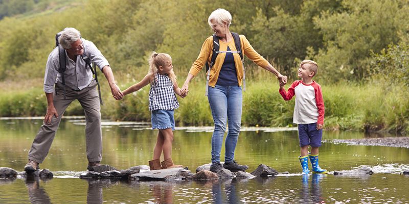 A family helping each other across a river on stepping stones