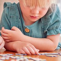 A young girl and parent doing a jigsaw