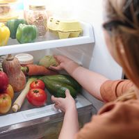 A young person taking food out of a fridge