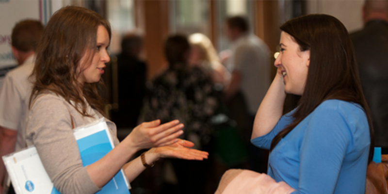 Two colleagues chatting at a conference