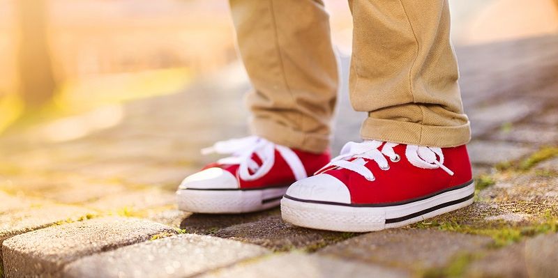 A close up of a pair of children's feet standing near a kerb