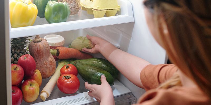 A young person taking food out of a fridge