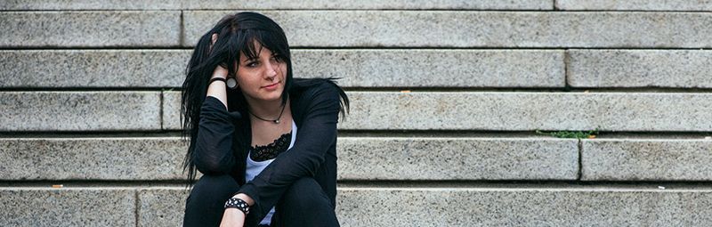 A teenager sitting on some steps outside