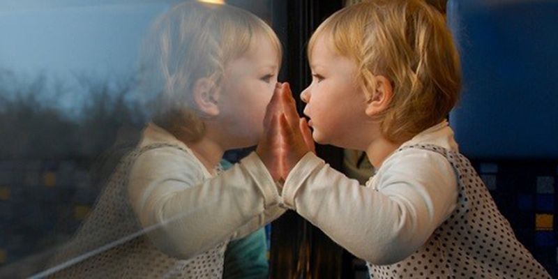 A toddler looking through a train window